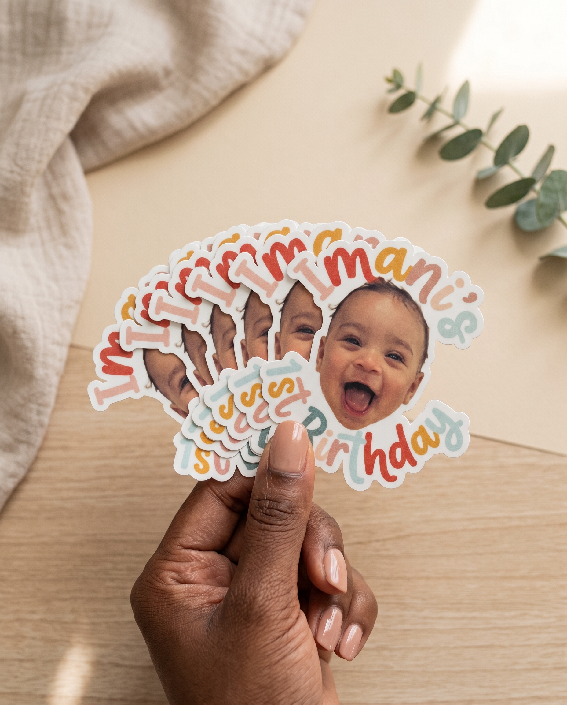 Hand fanning a stack of Imani's 1st Birthday arched-name stickers